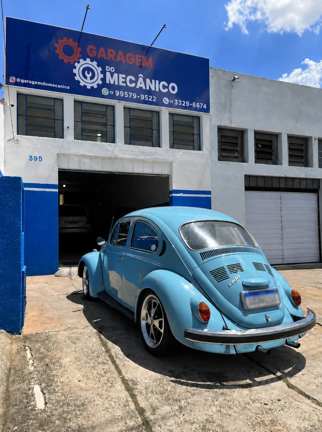 Fusca azul estacionado em frente à fachada da Garagem do Mecânico